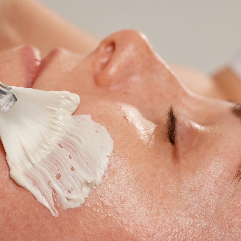 Professional face care brush for cosmetic procedures that evenly distributes the cream for the face of a girl at a beautician's appointment. Care cosmetics